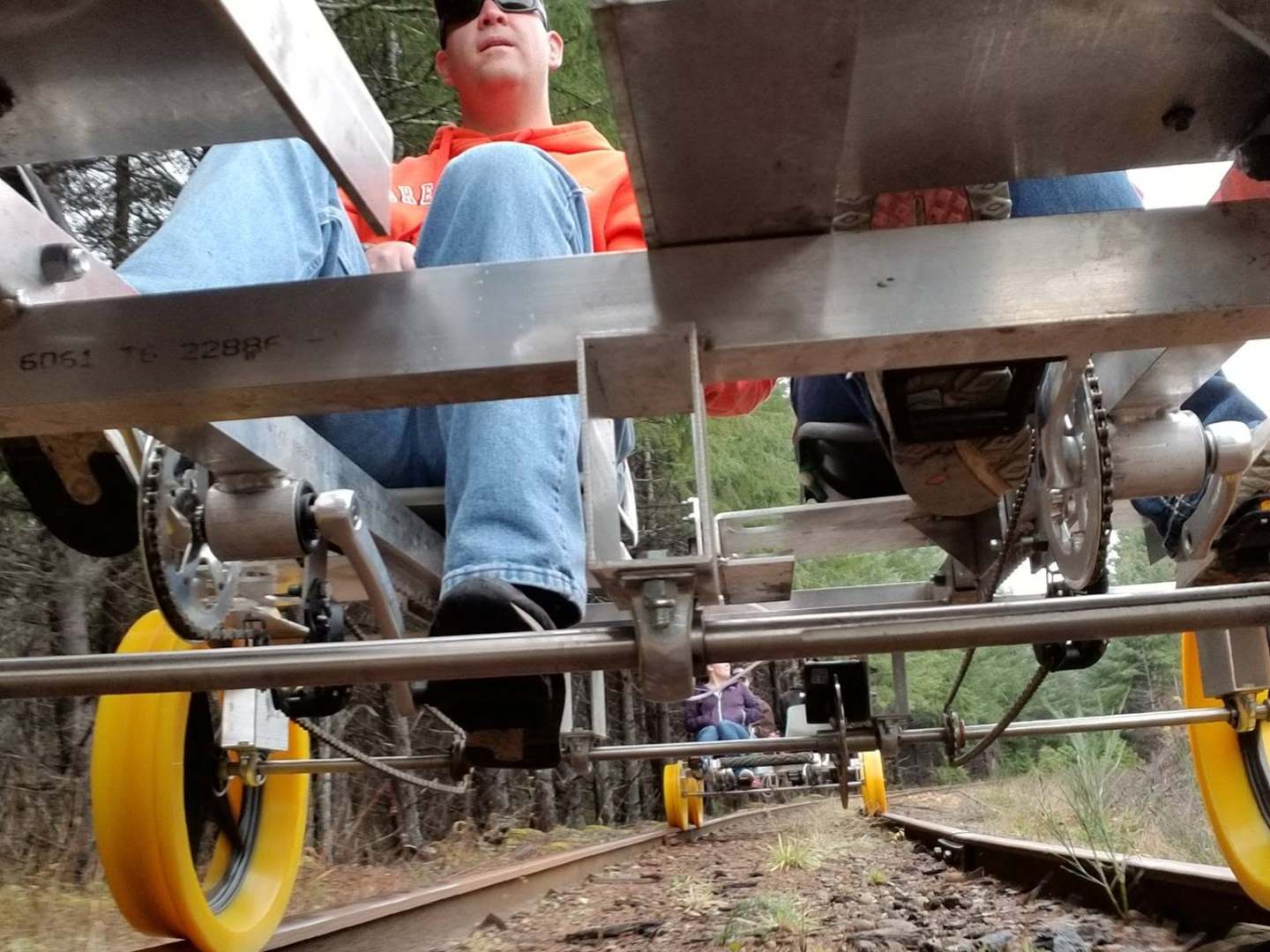 People riding on a pedal-powered rail bike with yellow wheels on a track.