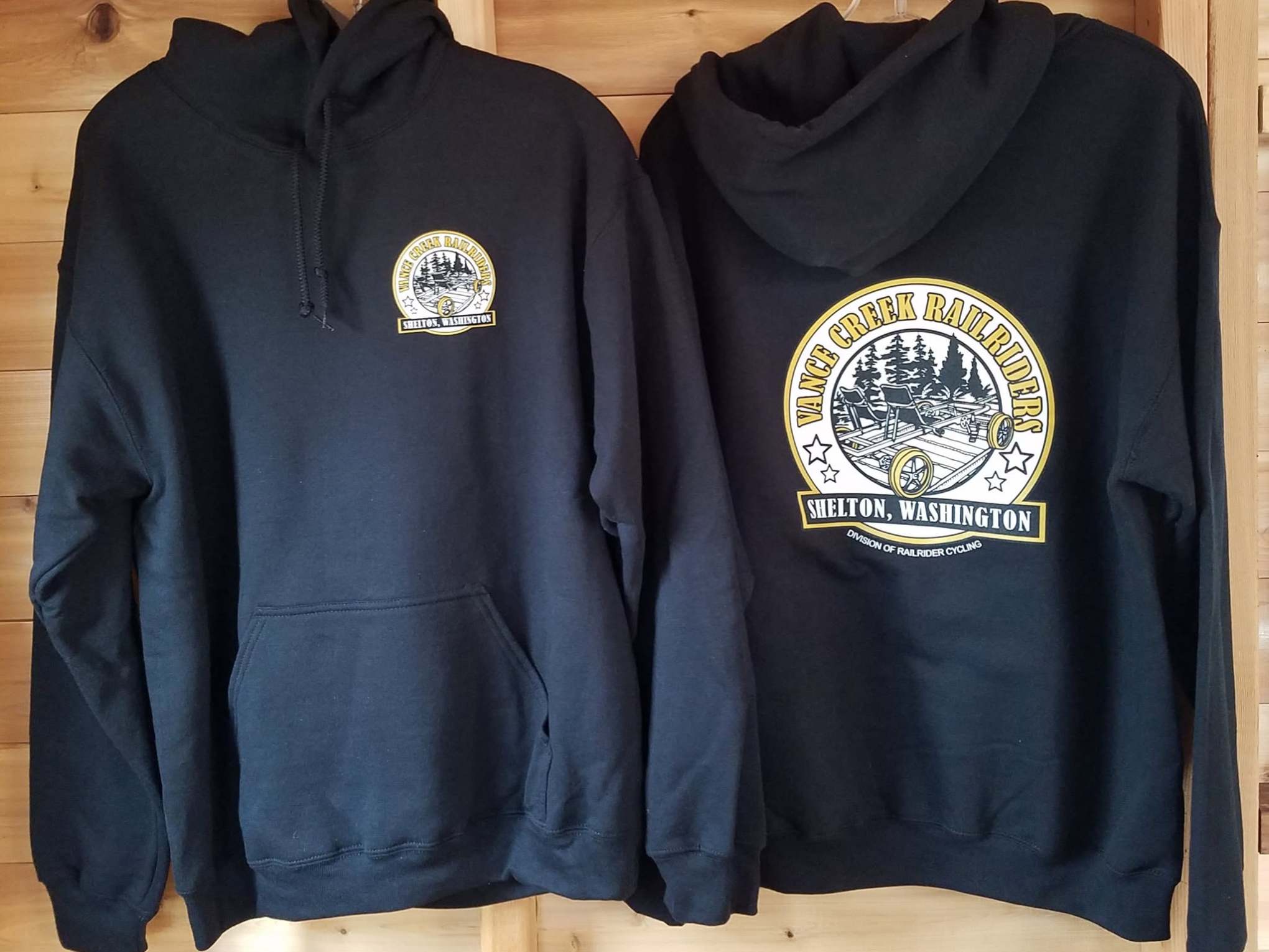 Two black hoodies with yellow 'Mason County Railroad' logos on a wooden background.