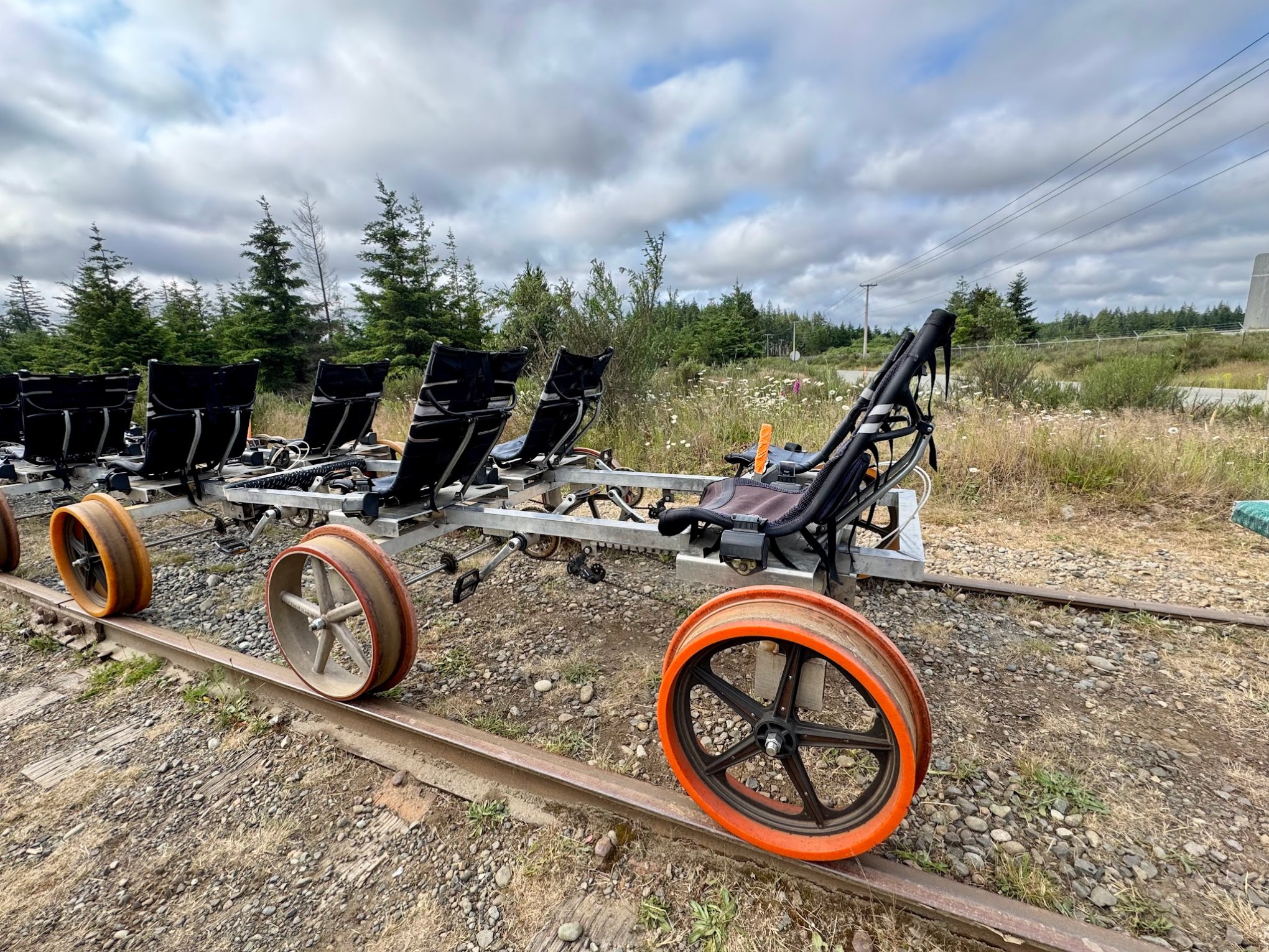 Railbike with multiple seats on a track in a rural landscape.